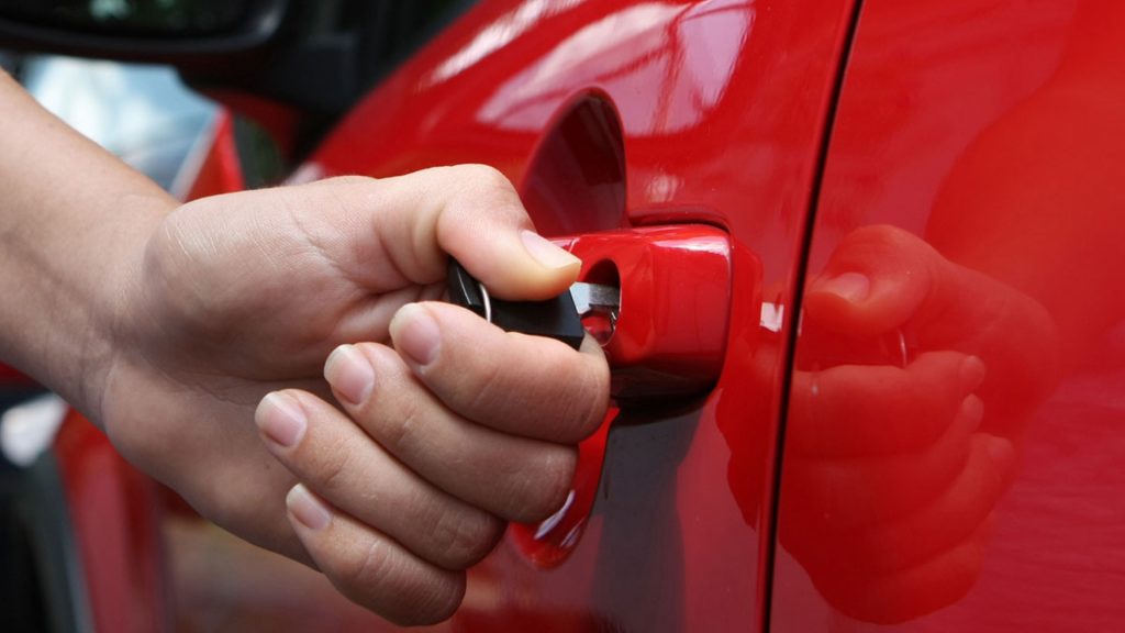 A driver unlocking a car with a mechanical key