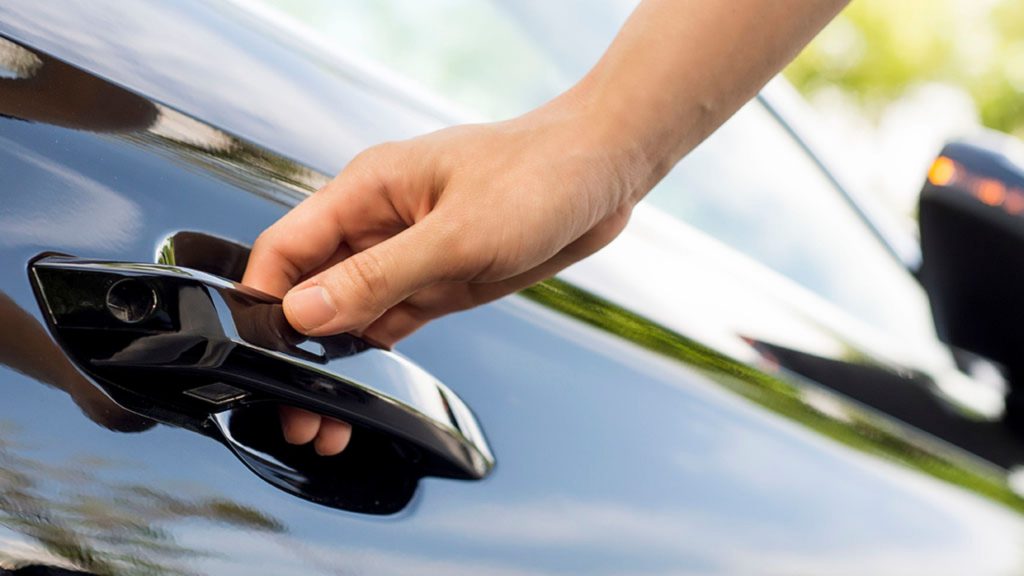 A close-up of a user opening a car door lock