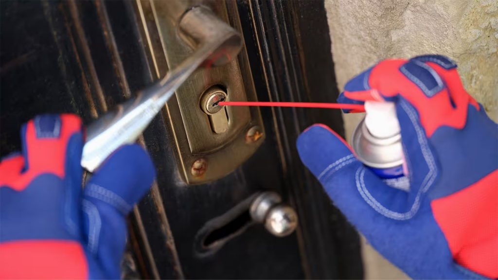 A locksmith doing lock lubrication on a residential door lock

