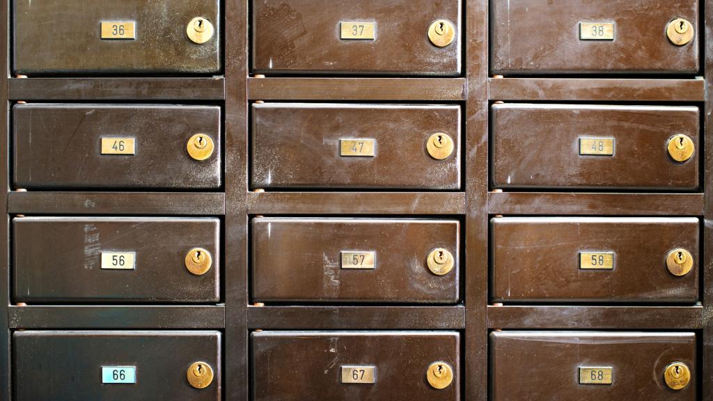 Close-up of apartment mailbox units with numbered compartments and brass key locks, supporting a guide about rekeying or replacing a mailbox lock