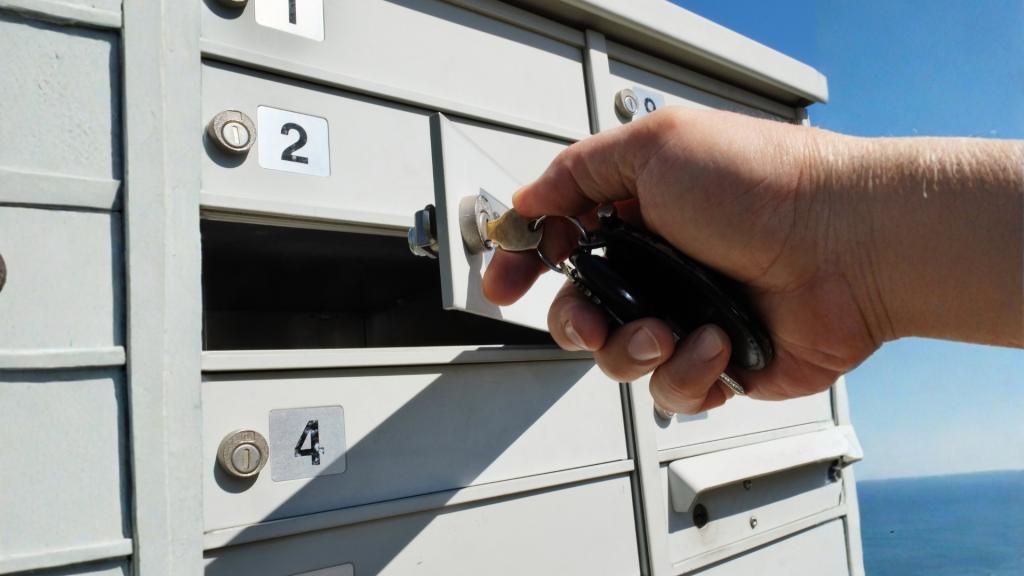 Close-up of a hand using a key on an outdoor mailbox lock, supporting a guide about why a mailbox won’t open and when locksmith help may be needed