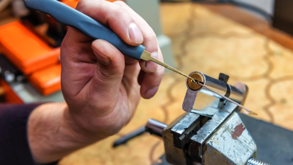 Close-up image of a locksmith adjusting a lock cylinder while explaining office rekey cost for commercial properties